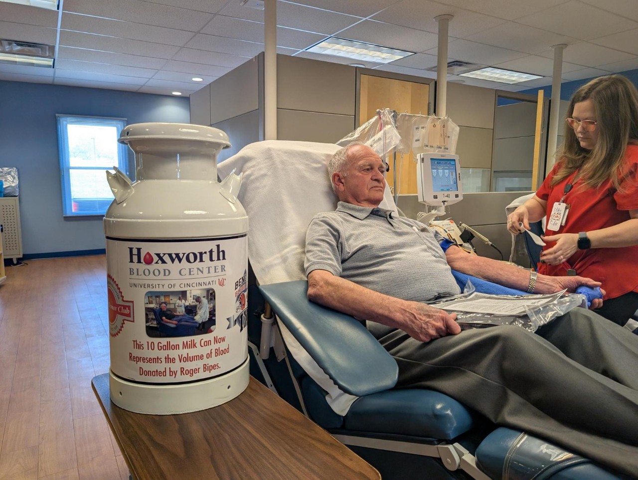Roger Bipes donating blood next to his 10 gallon milk can, to signify the amount of blood he has given.