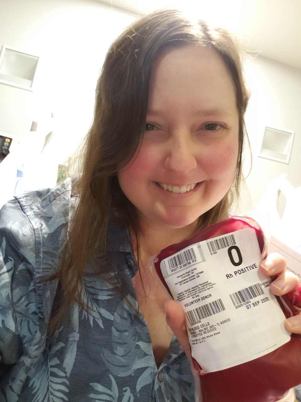 Alle Foster smiling while holding a bag of blood in the hospital